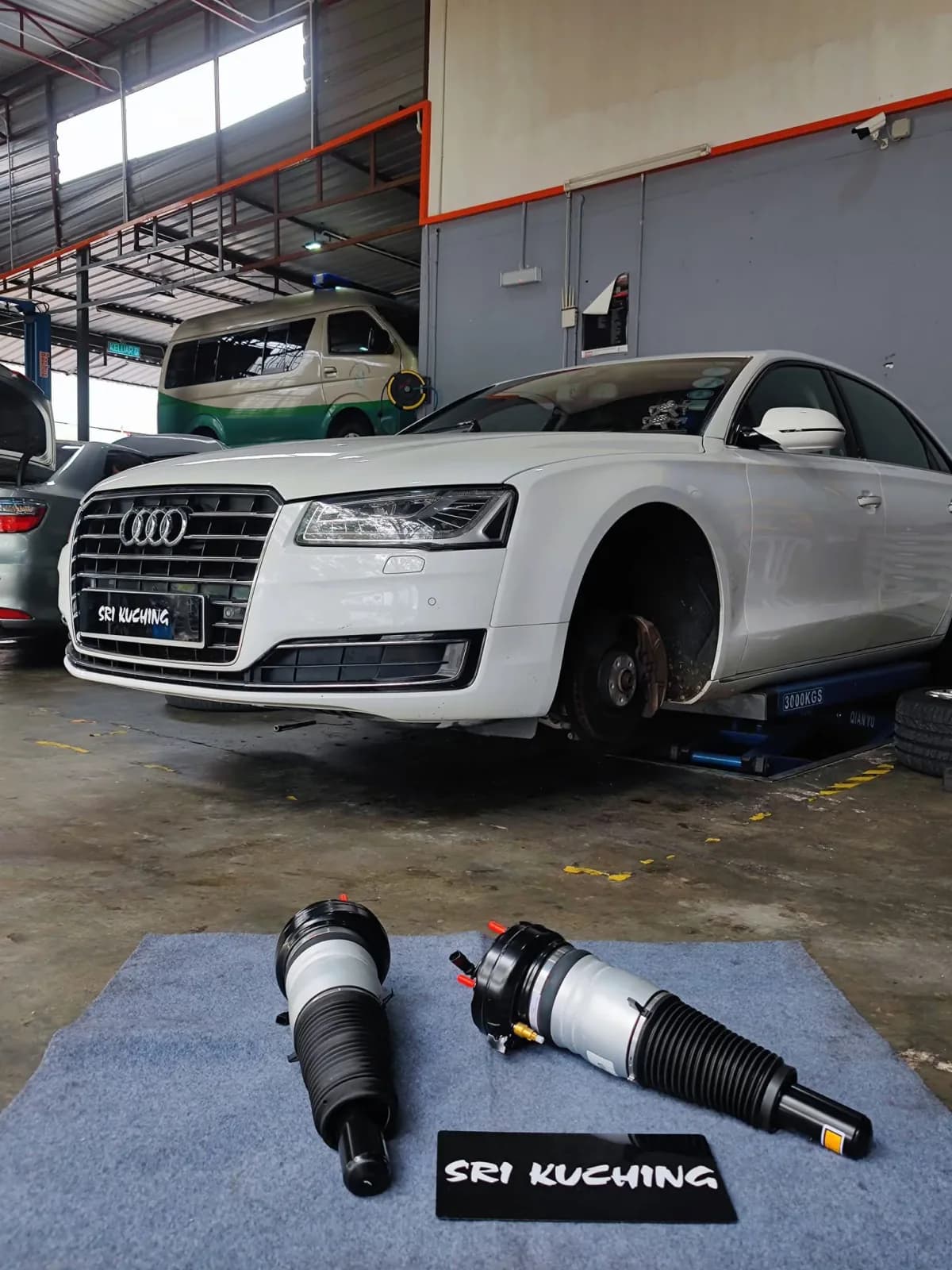 Audi A8 on a workshop lift with replacement front air struts in the foreground