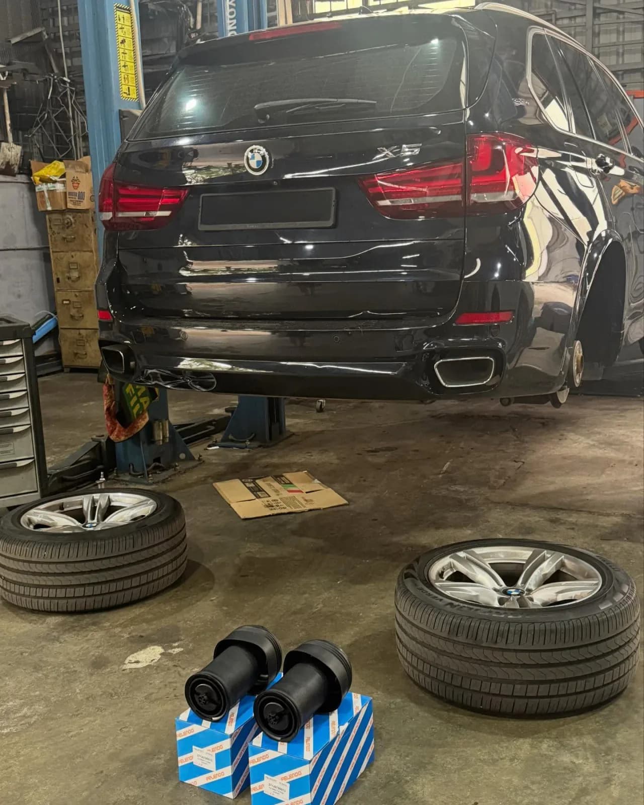 BMW X5 F15 raised at Sri Kuching with rear wheels removed and air springs beside the lift