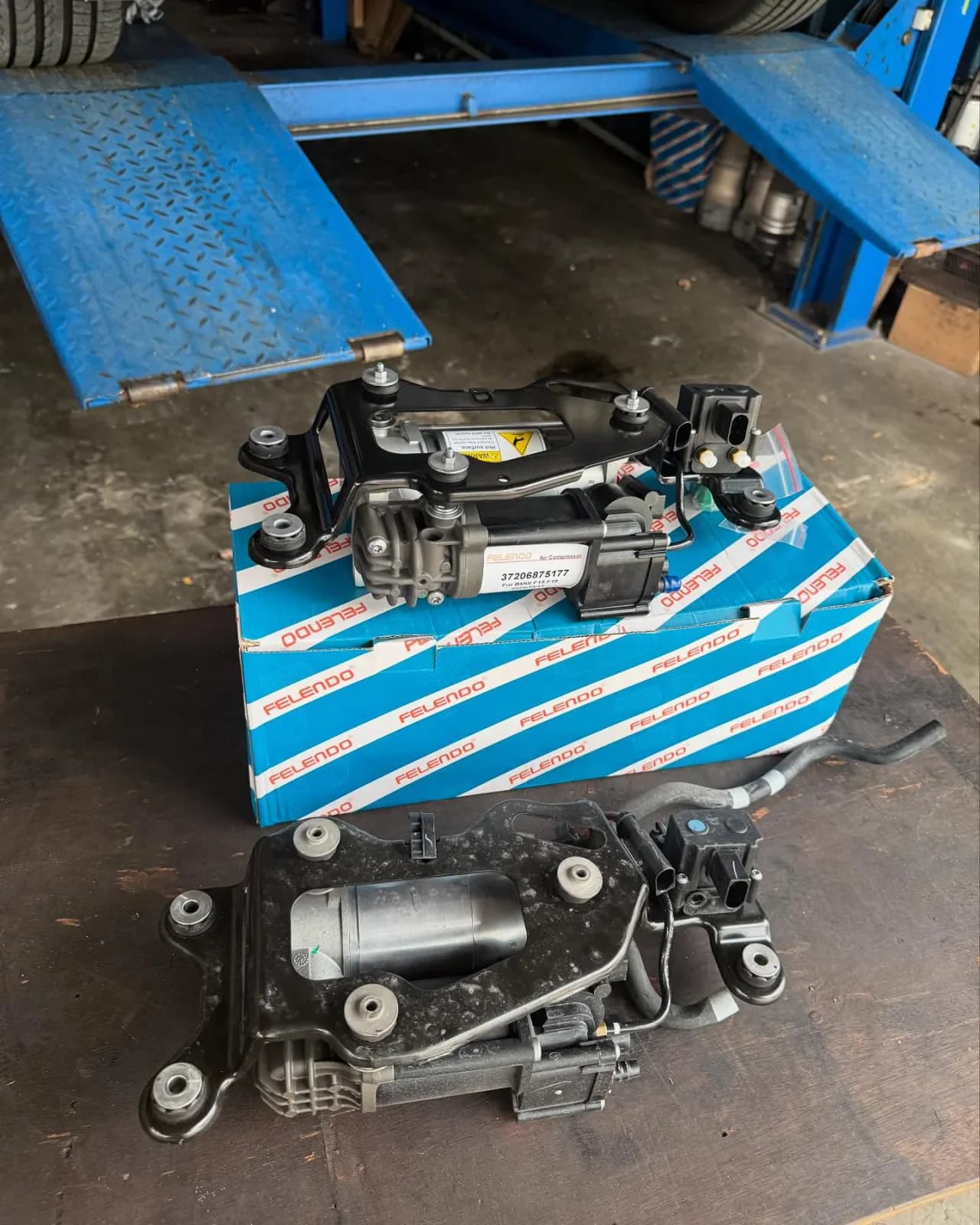 Air compressor assemblies photographed beside the lift during the BMW X5 F15 repair