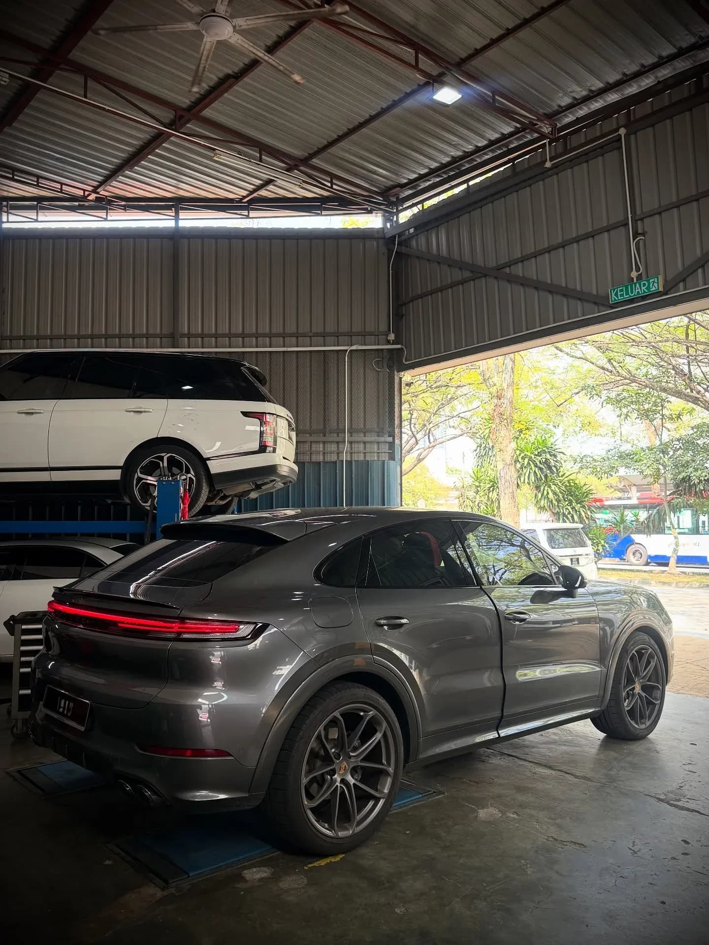 Rear three-quarter view of a grey Porsche inside the workshop near the entrance