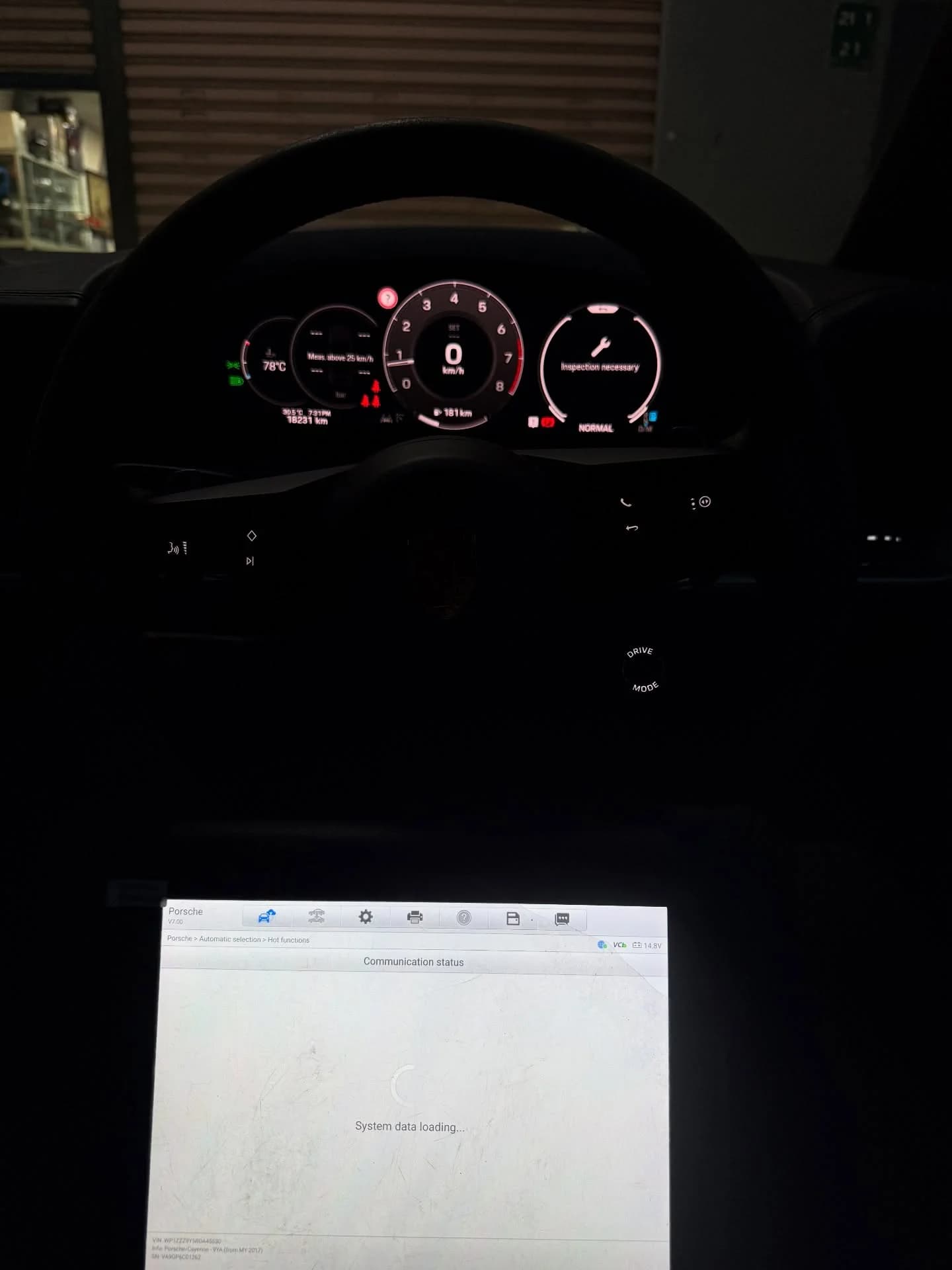 Diagnostic screen loading Porsche system data below the steering wheel, with an inspection reminder on the instrument cluster
