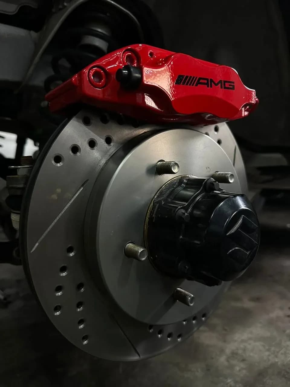 Red front brake caliper and drilled, slotted disc installed on the Suzuki Jimny with the wheel removed