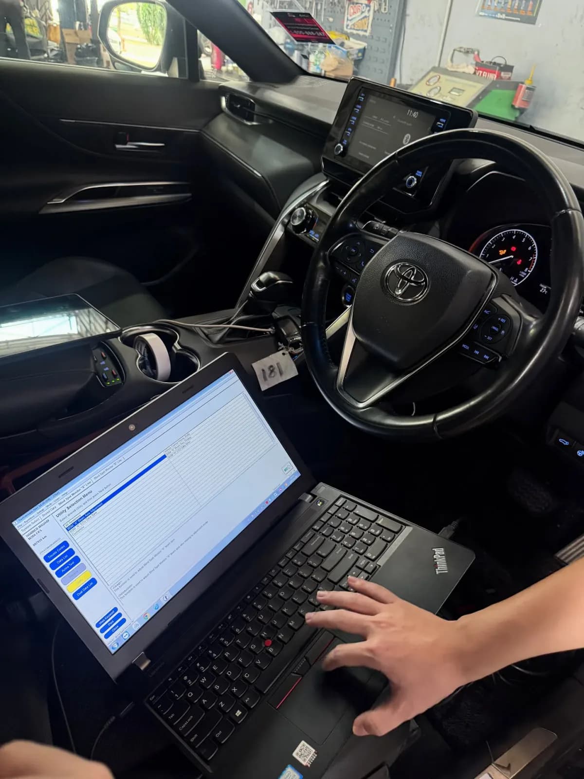 Technician operating a diagnostic laptop inside the Toyota Harrier