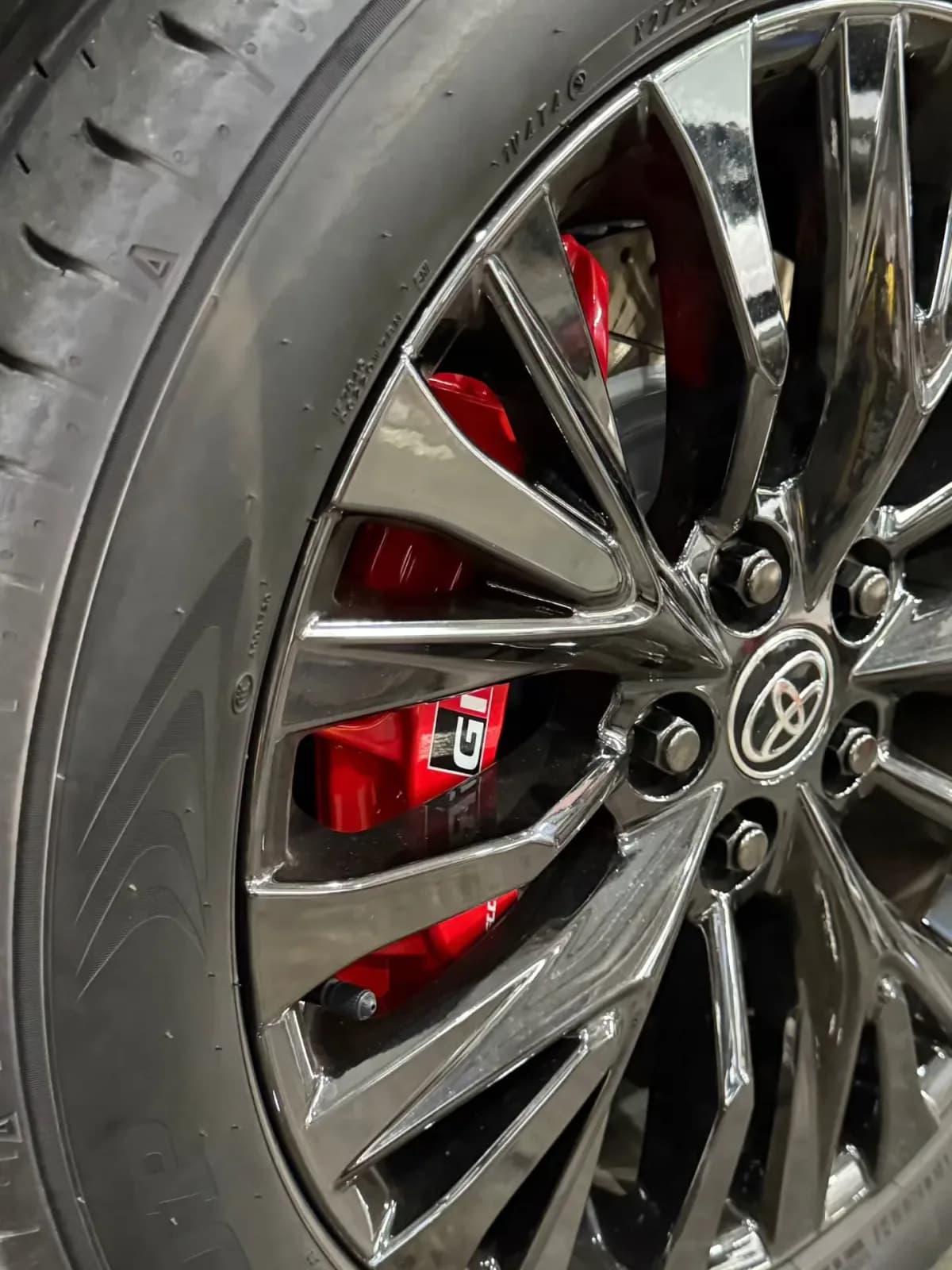 Red upgraded brake caliper behind a Toyota Vellfire wheel