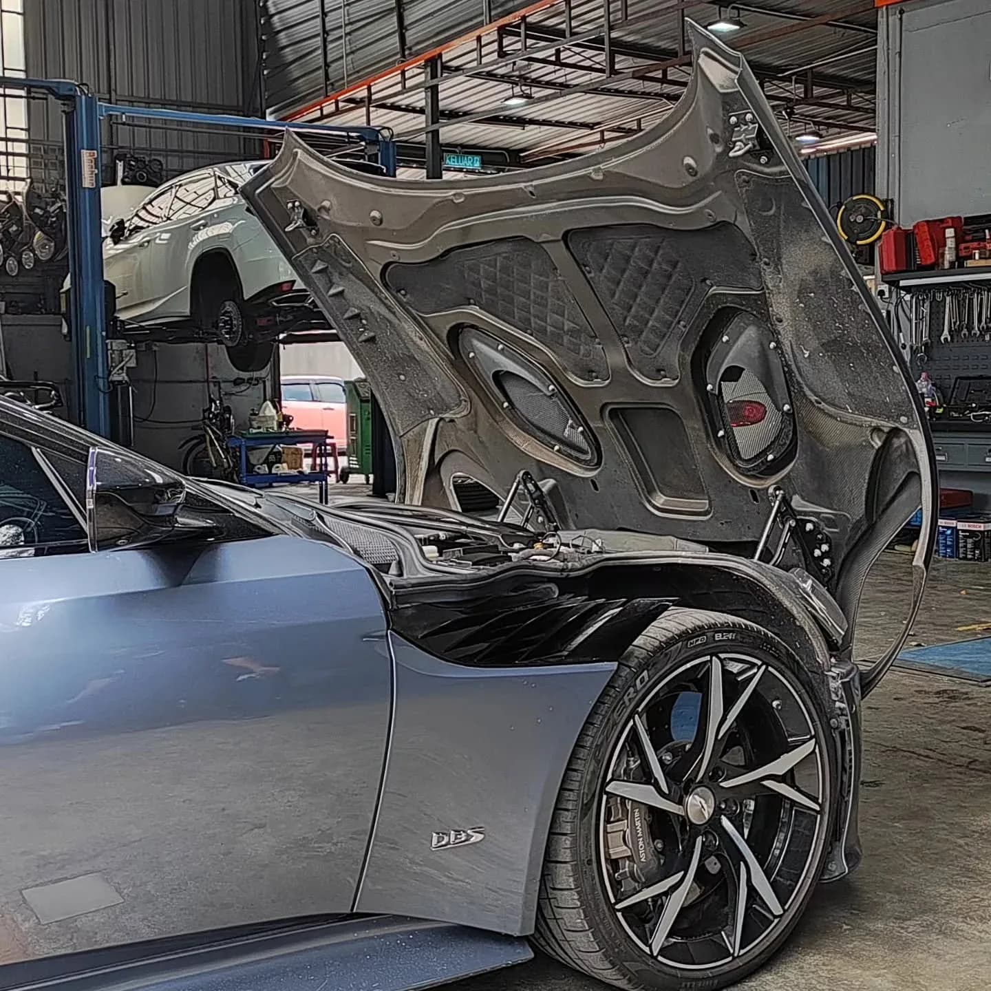 Aston Martin DBS with its bonnet open inside the workshop