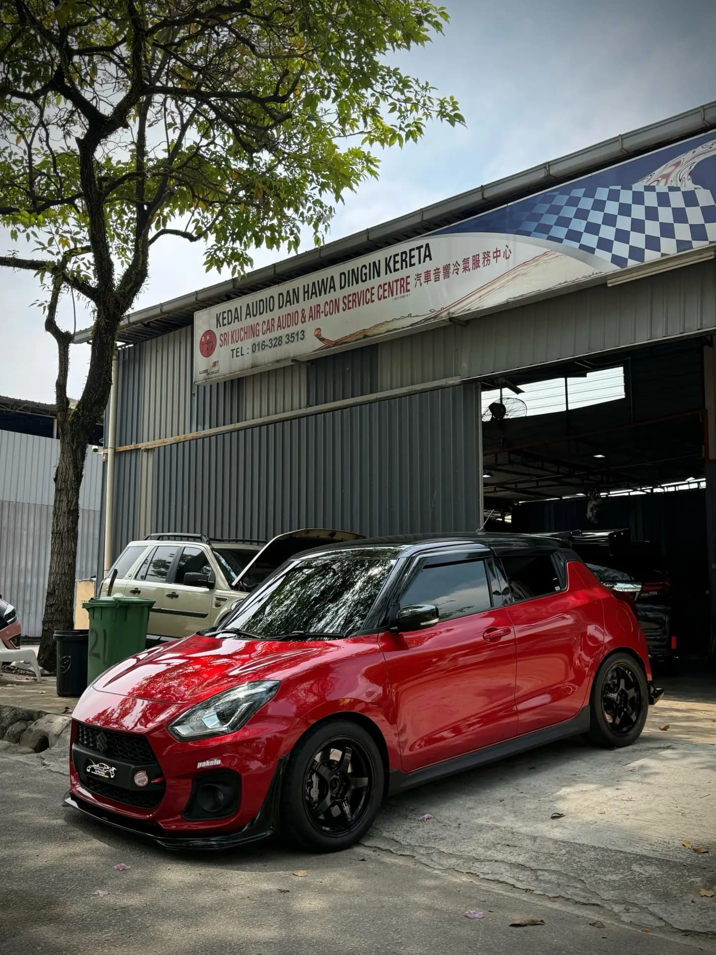 Red Suzuki Swift Sport ZC33S parked outside the Sri Kuching workshop