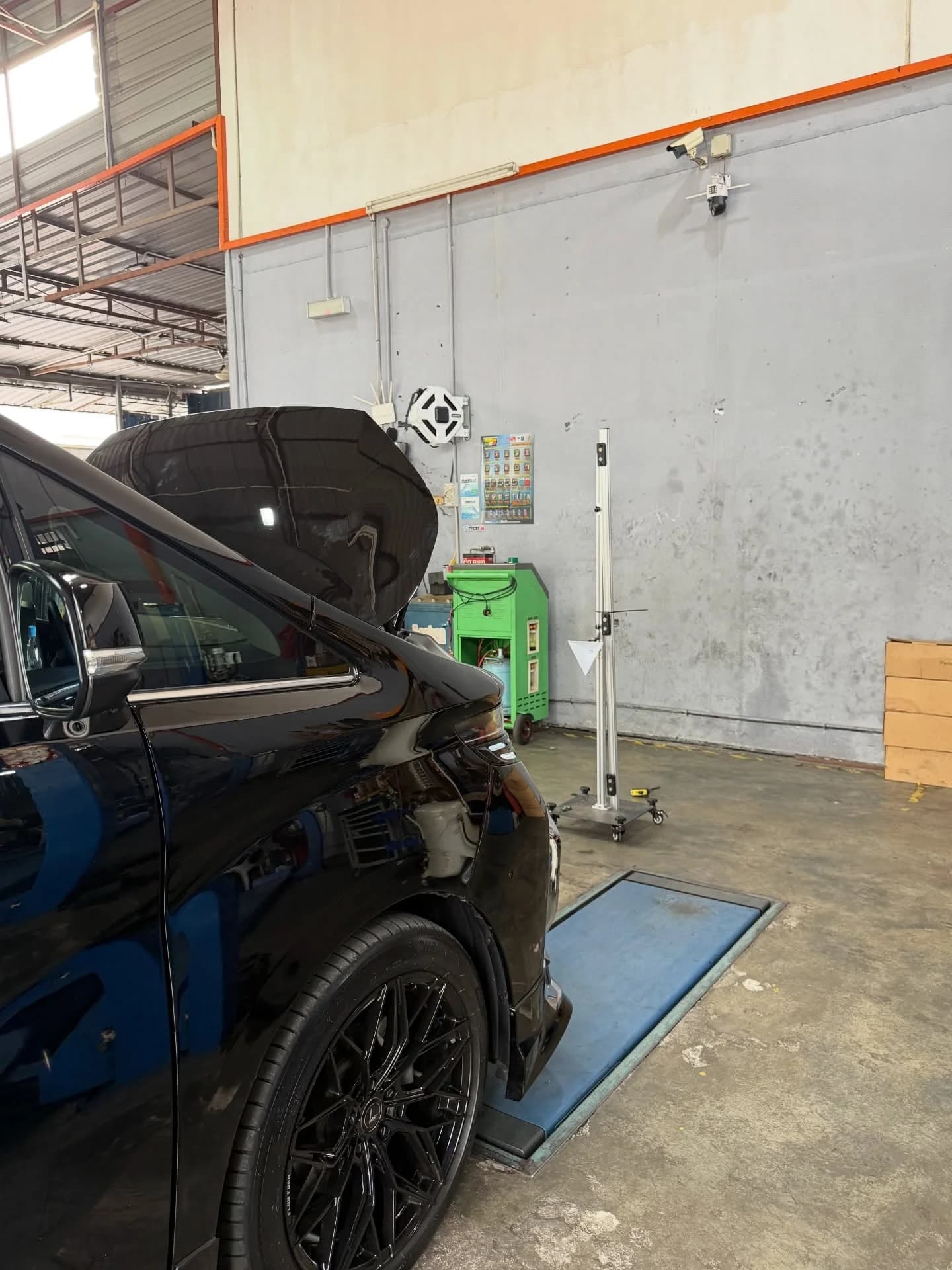 Toyota Alphard AGH30 with its bonnet open and a calibration target stand in the workshop