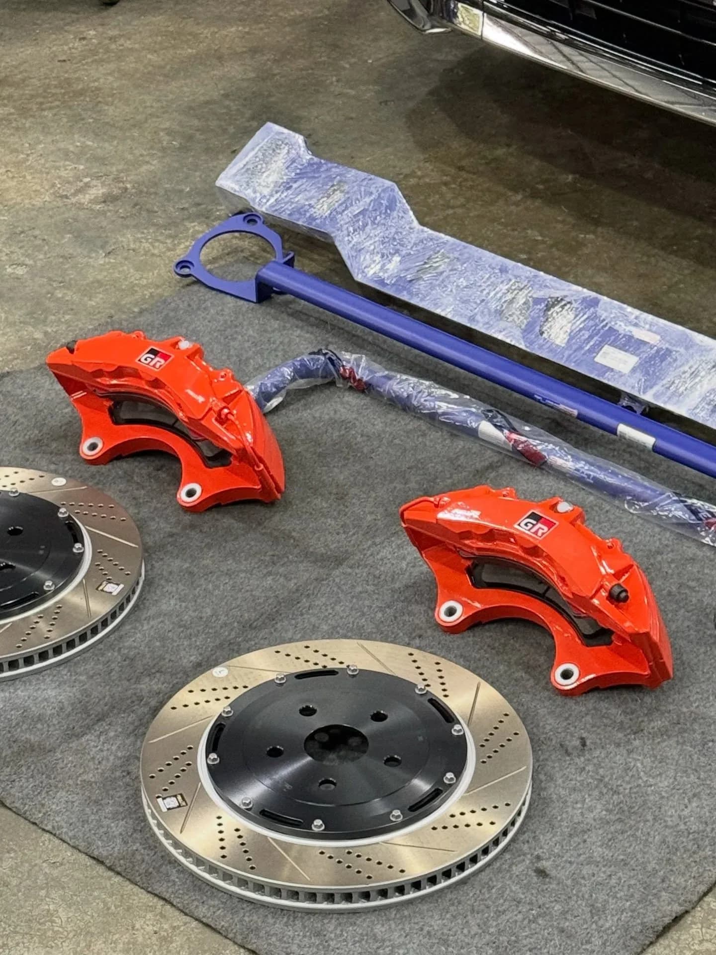Pair of red brake calipers and drilled, slotted brake discs laid out for the Vellfire AGH40